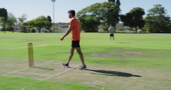 Indian male bowler taking run-up on pitch, releasing ball at batsman, questioning umpire call