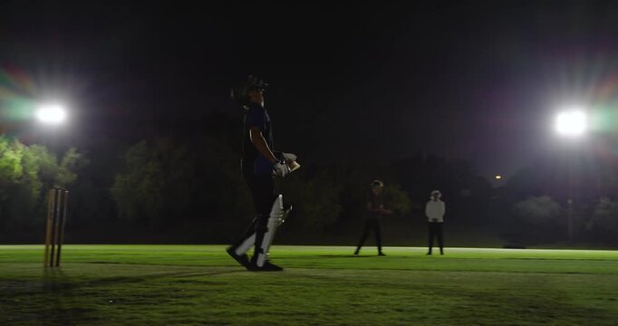 Male bowler delivering and cheering after wicketkeeper catching edge, floodlights