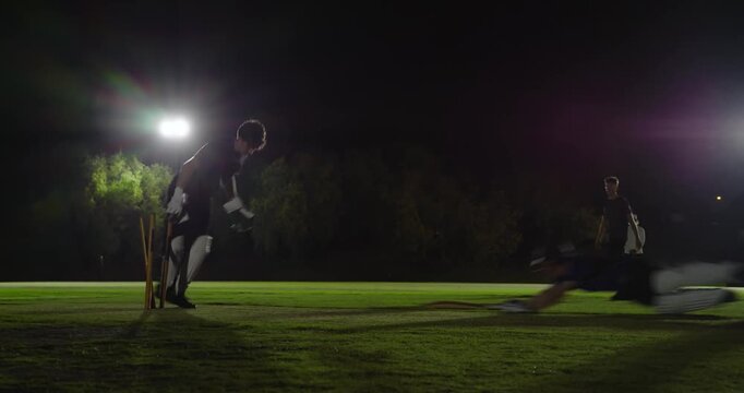 Bowler bowling ball, keeper catching, throwing at stumps to runout teen batsman night, copy space