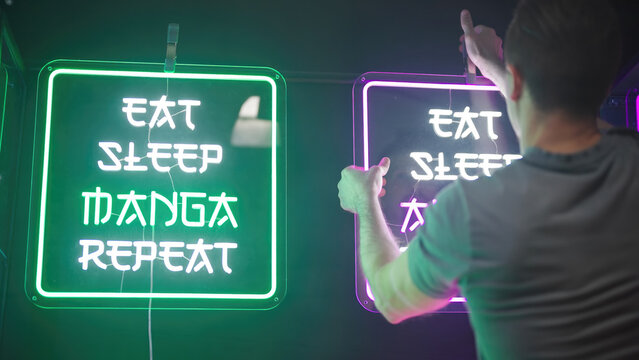 Person set up neon sign for anime and manga podcast studio