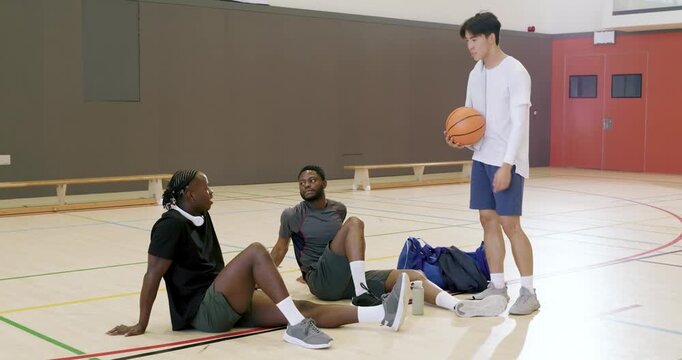 Entering court with basketball, man dribbling, joining diverse male teammates resting