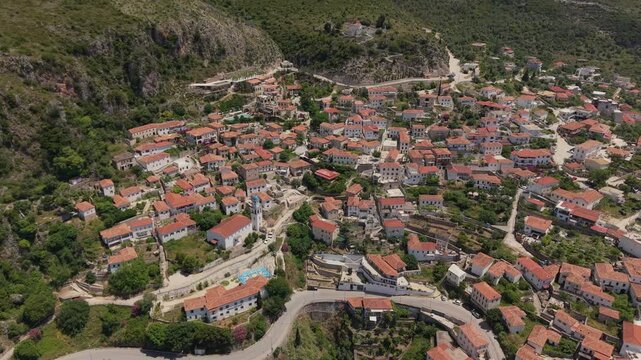 Aerial view of the traditional stone houses with red-tiled roofs and a church bell tower in the hillside village of Dhermi, Vlore County, Albania.