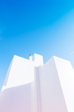 A striking example of minimalist architecture. The clean, angular lines of the white building are softened by natural sunlight and shadows, creating a simple yet powerful and aesthetic composition.