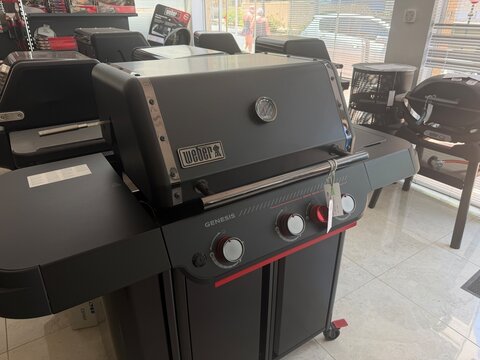 Calvia, Spain - June 15, 2026: Weber Genesis gas grill displayed in a retail showroom with modern design and sleek black finish, showcasing multiple burners and control knobs