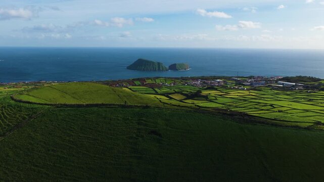 Terceira Island, Azores, Portugal - Patchwork Green Fields Extend Toward the Atlantic Ocean with Pico Dona Joana Rising Offshore Beneath a Bright Blue Sky - Drone Flying Forward