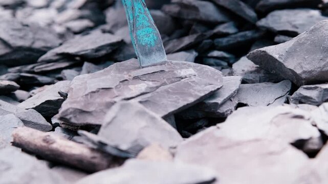Super slow motion at 180fps from a low angle: the chisel drives into Jurassic shale, debris kicking up close to the lens. A dramatic ground-level view of fossil hunting in Holzmaden, Germany.