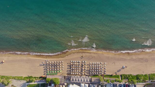 Static top down aerial shot of Kourouta beach, Greece. Luxury hotel beach umbrellas, bathers on shore and swimmers. Clear water