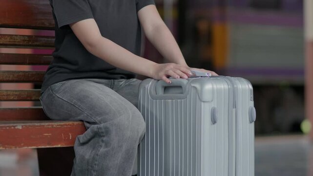 Traveler sitting on a bench with a suitcase at a train station, ideal for waiting, departure, rail travel, tourism, public transport and journey concepts