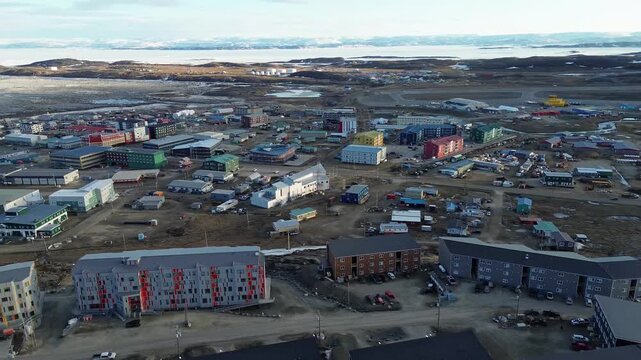 Wide, comprehensive aerial view showing multi-family apartment complexes, houses, and local utility infrastructure in central Iqaluit.