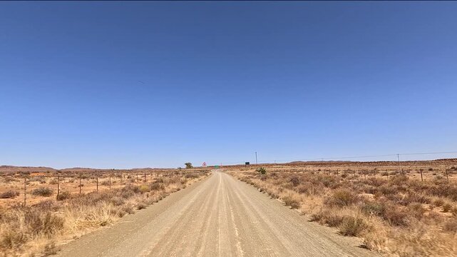 Vehicle approaches a T-junction on a dirt road, South Africa's arid Karoo region