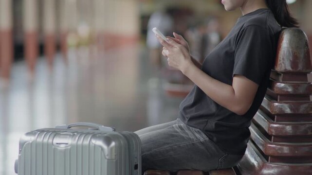 Traveler using a smartphone at a train station, ideal for travel app, online ticket, navigation, railway journey, tourism, public transport and trip planning concepts