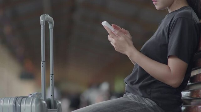 Traveler using a smartphone at a train station, ideal for travel app, online ticket, navigation, railway journey, tourism, public transport and trip planning concepts