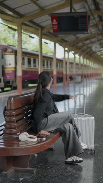 Traveler sitting on a bench and waving at a train station, ideal for goodbye, greeting, railway journey, tourism, waiting, departure and travel concepts