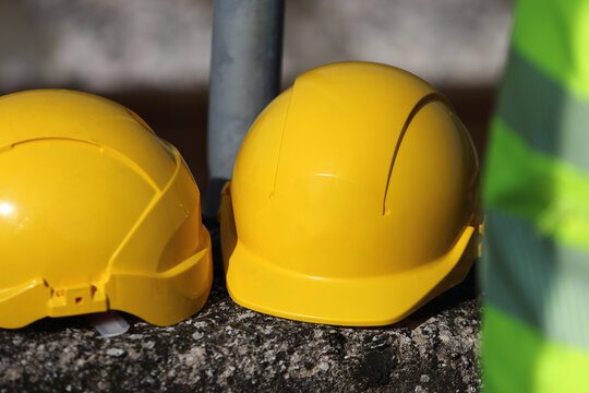 Two yellow hard hats resting on a concrete wall at a construction site