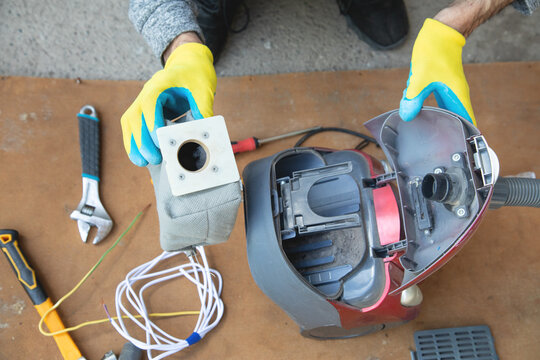 Caucasian master repairing vacuum cleaner. Vacuum cleaner repairing