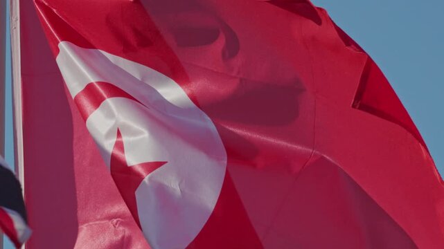 National flag of tunisia waving in the wind against blue sky