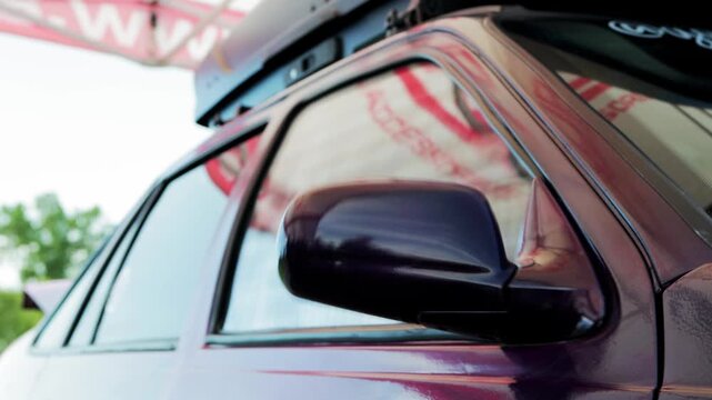 Dynamic view of purple car door, window glass, and side mirror rapidly shaking, demonstrating immense vibration effect of car audio system with loud bass from subwoofer. Distortion visible on tent ref