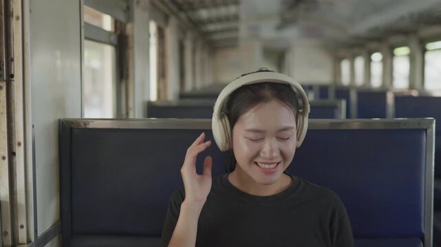 Traveler listening to music with headphones inside a train, ideal for travel lifestyle, relaxation, entertainment, commuting, rail journey and passenger concepts.