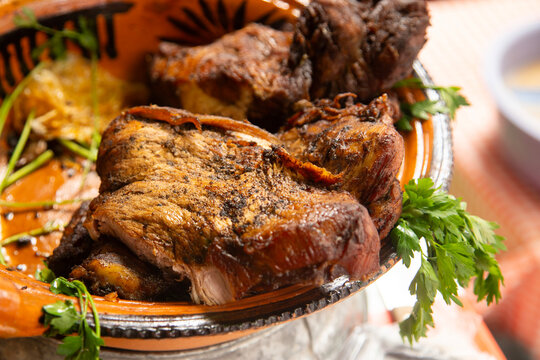 Close-up of tender, roasted cochito horneado served on a rustic clay platter with fresh parsley garnish in Chiapas del Corzo, Mexico.