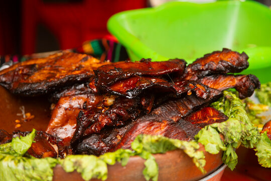 Close-up of tender, roasted cochito horneado served on a rustic clay platter with fresh parsley garnish in Chiapas del Corzo, Mexico.