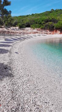 Vertical Curved Pebble Beach Shore Line With Thatch Parasols And Calm Sea, Ksamil - Albania.