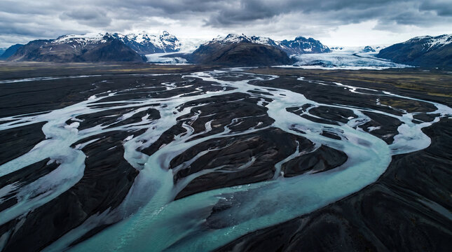 Aerial view of braided rivers flowing through a mountainous landscape.
