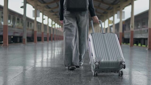 Traveler walking with a rolling suitcase at a train station, ideal for tourism, public transport, travel journey, commuting and vacation concepts.