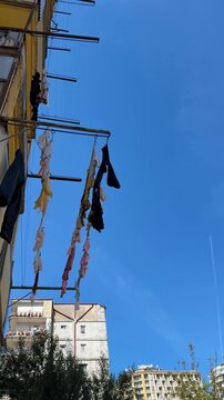 Laundry hanging from clotheslines on urban building facade with clear blue sky background