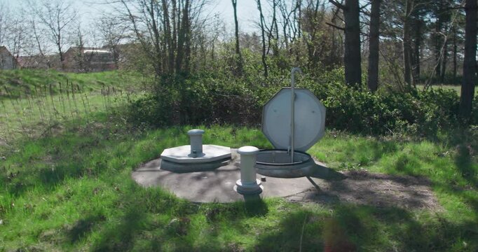 Drilled water well with water spring flowing up from the ground. Natural groundwater source emerging from a bored well, fresh and clean water supply from underground.