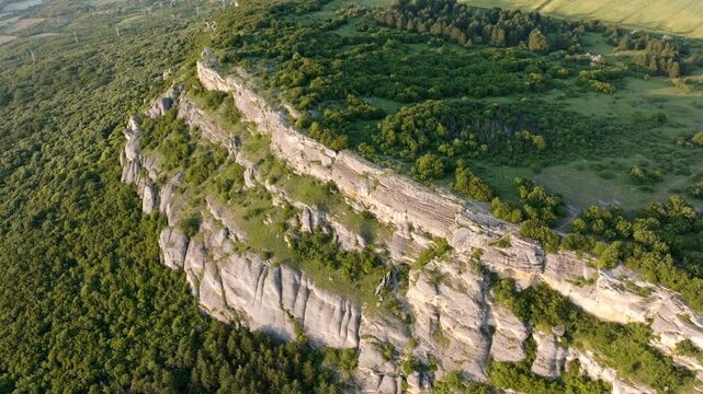 Madara cliff face limestone wall vertical rock formation aerial Bulgaria UNESCO heritage Shumen slow motion golden hour travel nature geology dramatic texture escarpment forest