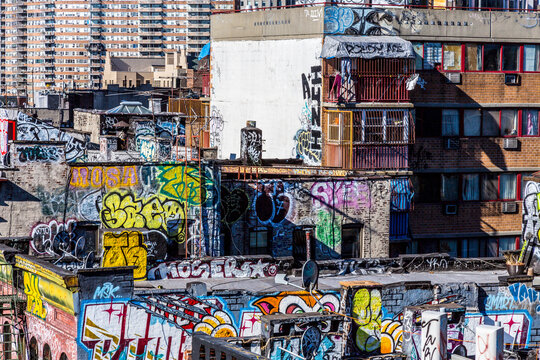Vibrant graffiti art adorns industrial brick building rooftops in Chinatown, capturing the gritty urban lifestyle and creative culture of Lower Manhattan, New York City, USA.