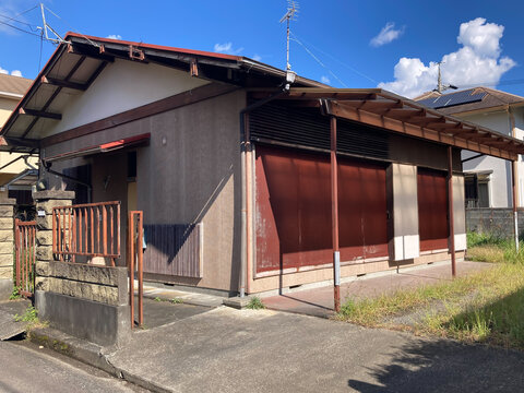 青空をバックした平屋建て一戸建ての空き家住宅の外観、古い木造住宅の空家