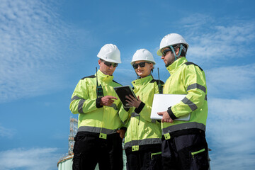 Fototapeta premium Engineer maintenance team at refinery industrial site group discussion clear sky collaboration on safety procedures
