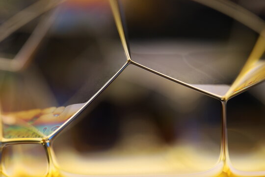 Microscopic golden fluid matrix with precise geometric cell dividers and soft reflection. Scientific macro photography showcasing a stable liquid network. Clean, metallic golden-toned mem