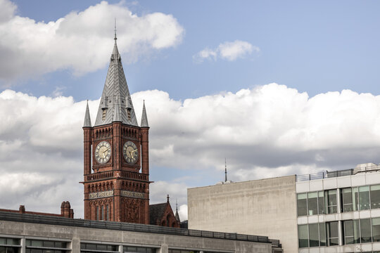 View of the historic red brick Victoria Building clock tower at the University of Liverpool under a cloudy blue sky in Liverpool, England, United Kingdom.