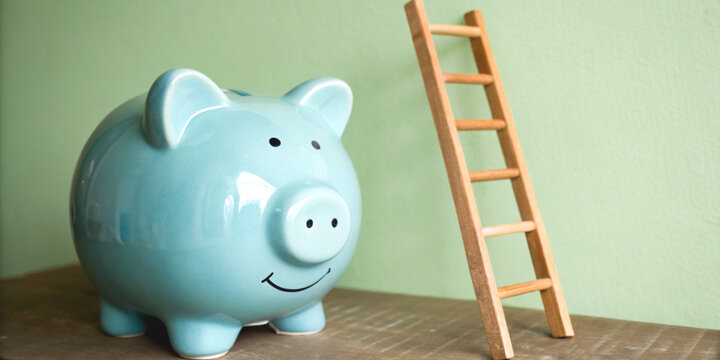 Financial growth and setting savings goals with the blue piggy bank next to the stairs