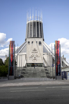 View of the modernist Liverpool Metropolitan Cathedral with its iconic lantern tower and colorful banners under a blue sky in Liverpool, England, United Kingdom.