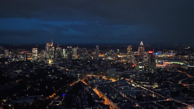 Frankfurt skyline glowing with office lights during twilight, city's dynamic urban landscape and modern architecture under evening sky in financial center