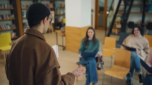 People are learning in a library during a group session with a speaker standing in front of them and sharing information