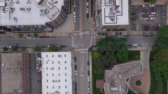 Top down urban landscape of an american city neighborhood with cars driving on the streets and building rooftops revealing unique architectural patterns