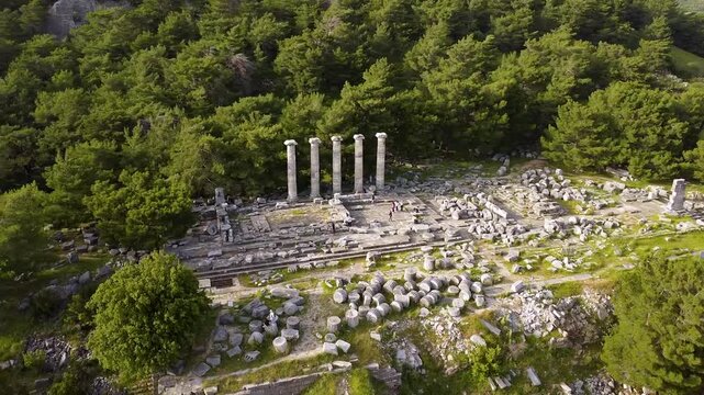 Drone flying over the ancient Greek ruins of the Temple of Athena Polias in Priene. The archaeological site is surrounded by a forest
