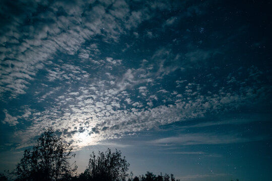 Moonlight glowing through altocumulus clouds at night