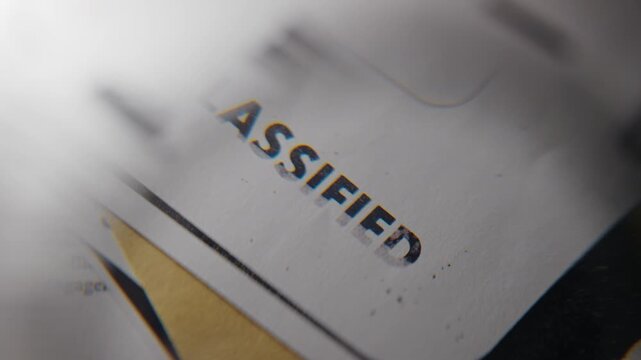 Close up on magnifying glass enlarging rubber stamp on classified document government top secret looking file with confidential intelligence information hidden or exposed by whistleblower or detective