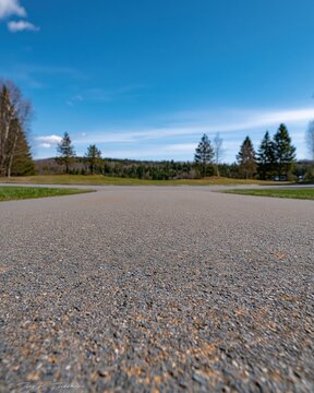Gravel path leading through a scenic landscape with trees and a blue sky
