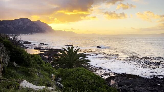 Vivid sunrise morning view from Hermanus coastal cliff over ocean and Walker Bay
