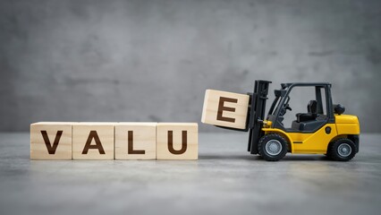 Fototapeta premium Small forklift toy completing the word VALUE with wooden blocks on grey background