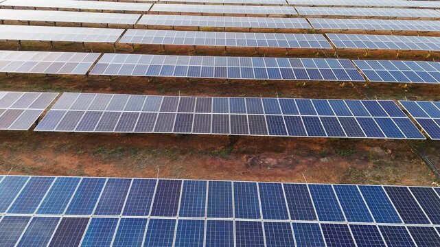 Cinematic drone tilt down shot revealing endless solar panels at a large renewable energy farm, showcasing sustainable electricity production and modern clean energy infrastructure.