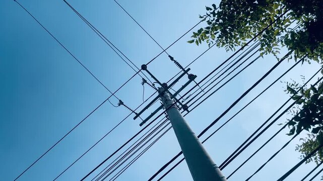 Electric utility pole against clear blue sky, power distribution infrastructure with overhead cables, minimalist outdoor scene and urban utility concept.