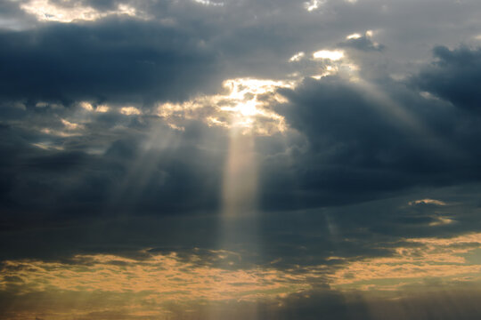 Single Ray of Sunlight Breaking Through Storm Clouds at Dramatic Sunset Sky