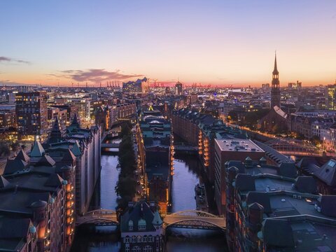Aerial view of Hamburg's Speicherstadt warehouse district at sunset with a view of the moated castle, the Poggenm&uuml;hlenbr&uuml;cke bridge and the Elbphilharmonie concert hall and St Michael's Church in the background, Hamburg, Germany